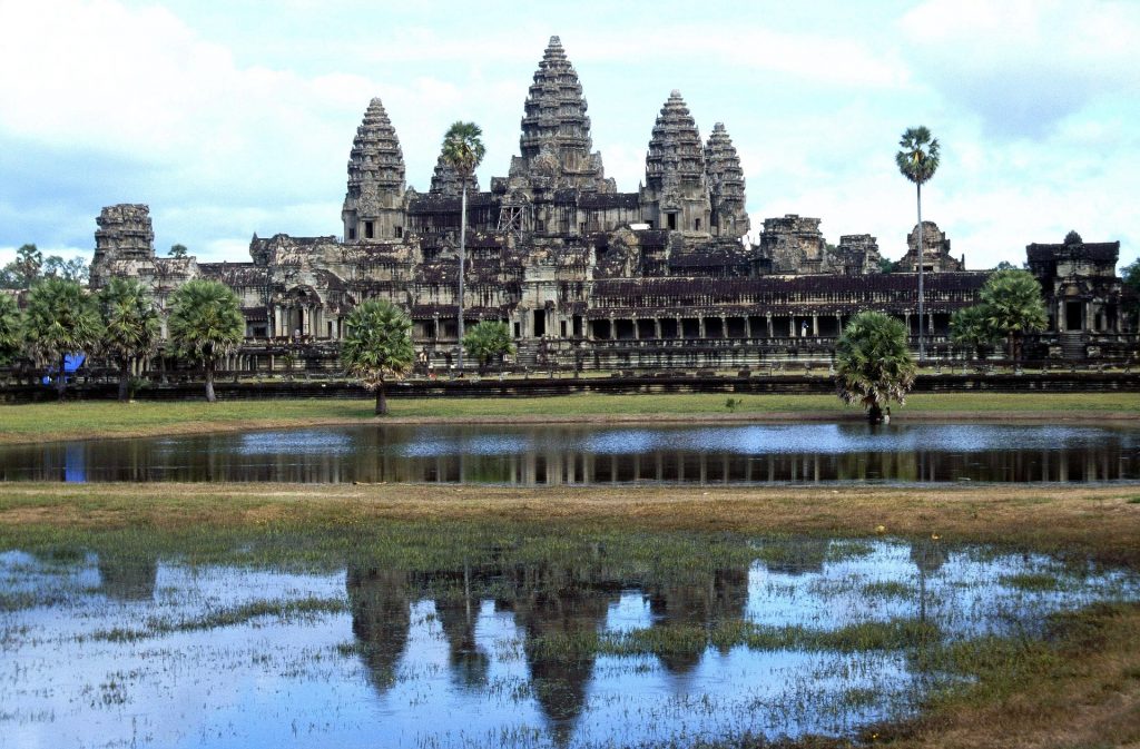 Image of Angkor Wat temple reflected on the water before it.