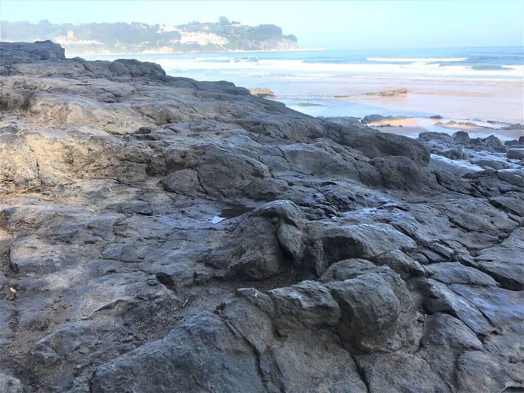 Dinosaur footprints with Llastres fishing village in the background