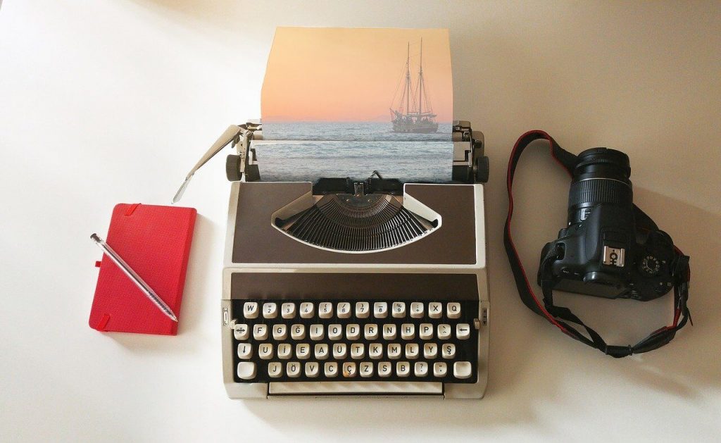 red travel journal, typewriter and camera