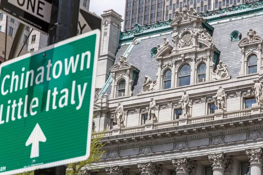 A sign saying Chinatown and Little Italy in front of an ornately decorated building in Chelsea, one of the best places to stay in New York City