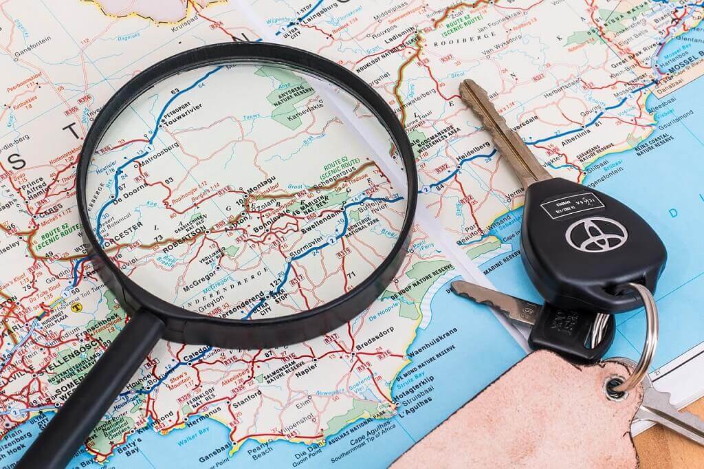 a map, car keys and a magnifying glass for a road trip.