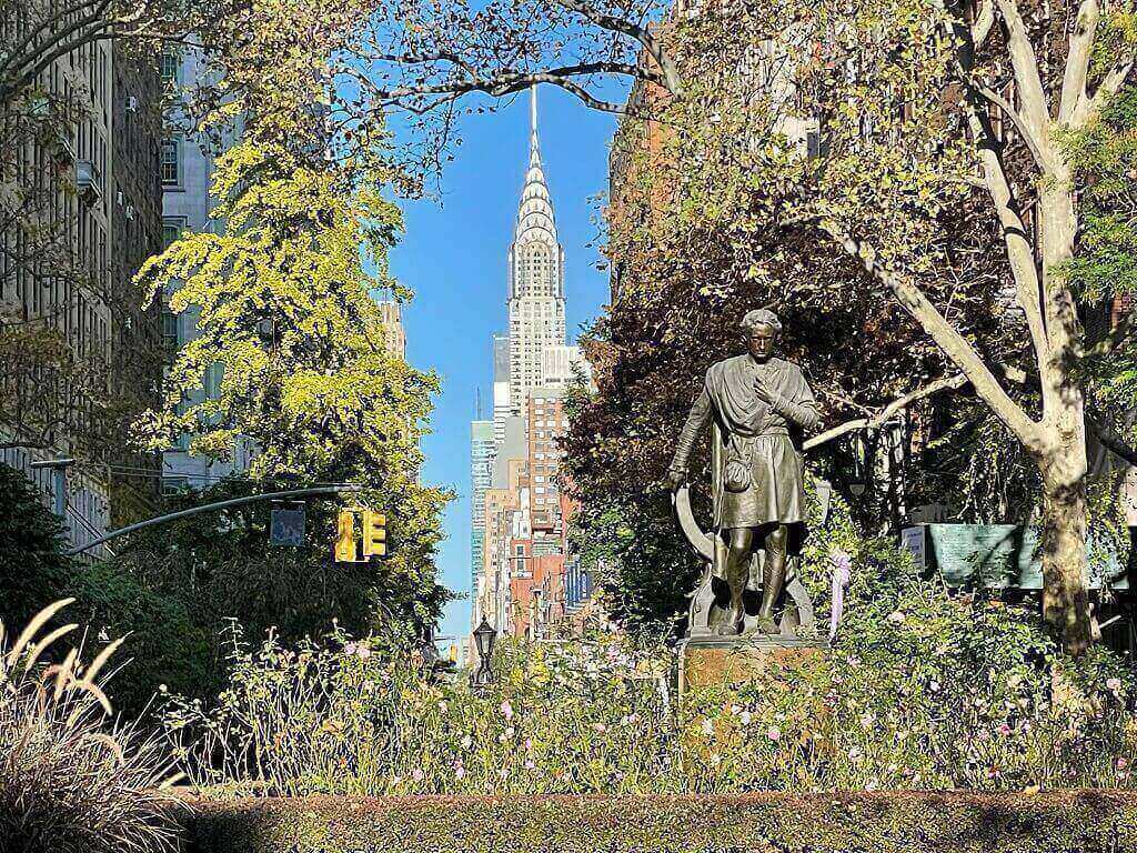 A park with a statue and the Chrysler building in NYC