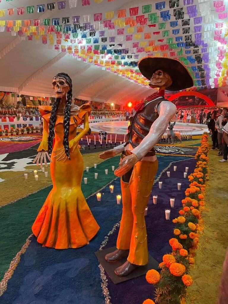 A Catrina and a Catrin celebrating Day of the Dead at a large altar